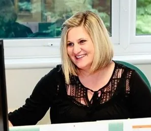 An ILS Case Management employee seated at a desk, smiling while focused on her computer screen